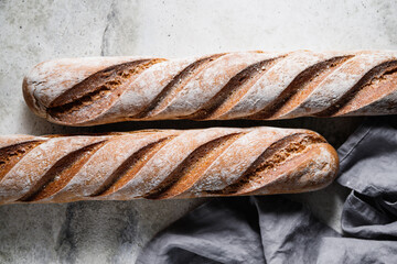 Top view of two brown baguettes on a concrete background.