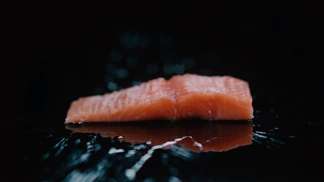 Pedazo de Salmon fresco cayendo en c&aacute;mara lenta en una lamina negra.  240 Fps HD