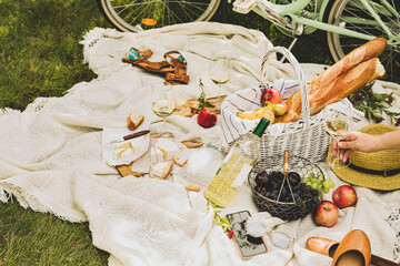 Summer - french style outdoor picnic. Wicker basket, food and wine.