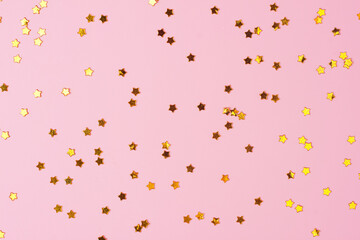 Fototapeta na wymiar Golden confetti on pink. Colorful Christmas or holiday background