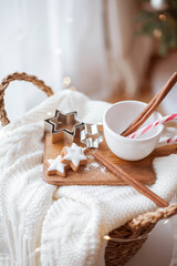 Fototapeta na wymiar Christmas decor. Mug, Christmas candy, Christmas cookies, knitted sweater, wicker basket against the background of a Christmas tree. Cozy holidays.