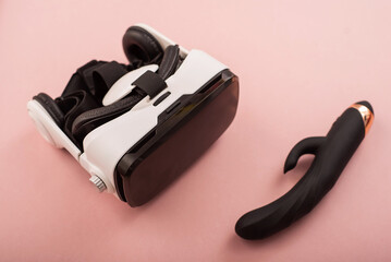 Clitoral vaginal black vibrator and virtual reality helmet on a pink background