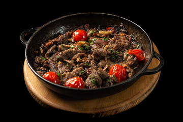 A frying pan with meat and vegetables on a tray