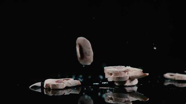 Hongos cayendo en c&aacute;mara lenta sobre una lamina negra con agua haciendo splash. 240 fps HD