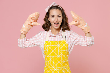Funny young woman housewife in yellow apron gloves potholders showing blah blah gesture ja jaja hands while doing housework isolated on pastel pink background studio portrait. Housekeeping concept. © ViDi Studio