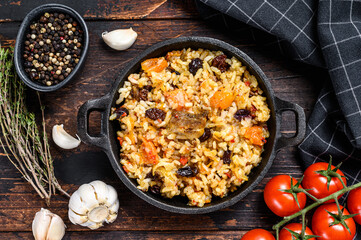 Pilaf in a pan. Central Asian cuisine Plov.  Dark wooden background. Top view