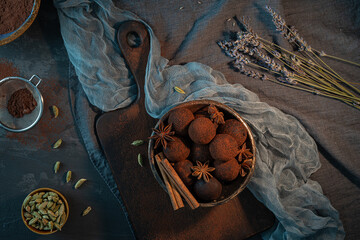 Craft chocolate truffles on plate with cocoa powder and anise, cinnamon, cardamom.