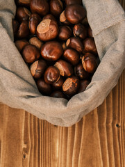 Vertical shot of chestnut in the linen bag on a wooden table 