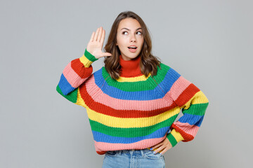 Shocked curious young brunette woman 20s wearing casual colorful knitted sweater standing try to...