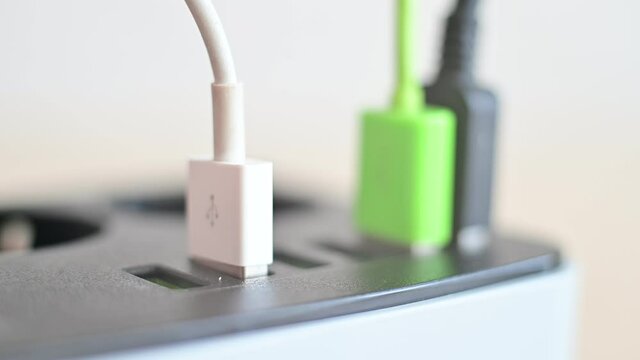 Modern convenient multi-port usb charger for devices. Close-up of inserted multi-colored cables in a power outlet. Macro.