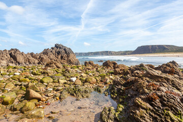 Fototapeta na wymiar Cliffs and sea rock on a beach, blue sky
