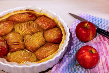 Freshly baked biscuit with apples and whole ripe red apples on the table.