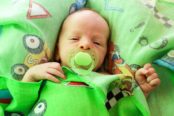 newborn baby child with green pacifier close up