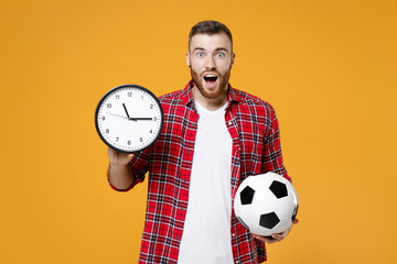 Shocked young man football fan in basic red checkered shirt cheer up support favorite team with...