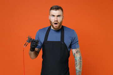Shocked worried professional tattooer master artist tattooed man in t-shirt apron hold machine...