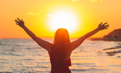 Black silhouette of a woman in a swimsuit on the background of the ocean. happy young woman on sea background enjoying freedom with open hands at sunset