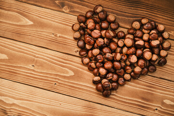Close up shot of chestnut side by side forming a heart on a wooden table 