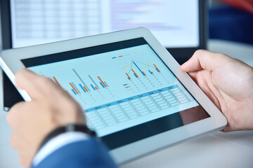 Hands using tablet device with business report