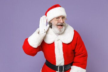 Curious Santa Claus man in Christmas hat red suit coat white gloves glasses try to hear you overhear listening intently isolated on violet background. Happy New Year celebration merry holiday concept.