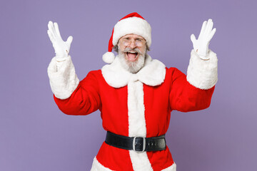 Fototapeta na wymiar Irritated angry Santa Claus man in Christmas hat red suit coat gloves glasses spreading hands screaming swearing isolated on violet background studio. Happy New Year celebration merry holiday concept.
