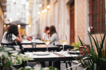 Two glasses of wine on a outdoor table, cozy evening, small street in Europe