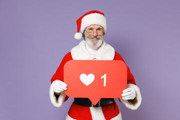 Funny Santa Claus man in Christmas hat red suit coat glasses hold huge like sign from social network heart form isolated on violet background studio. Happy New Year celebration merry holiday concept.