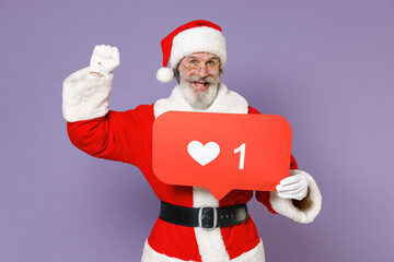 Excited Santa Claus man in Christmas hat suit hold huge like sign from social network heart form doing winner gesture isolated on violet background. Happy New Year celebration merry holiday concept.