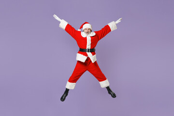 Fototapeta na wymiar Full length portrait of excited Santa Claus man in Christmas hat red suit coat gloves jumping spreading hands and legs isolated on violet background. Happy New Year celebration merry holiday concept.