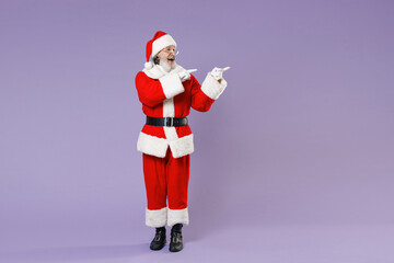 Full length portrait of Santa Claus man in Christmas hat red suit coat white gloves glasses point index fingers aside isolated on violet background. Happy New Year celebration merry holiday concept.