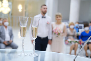Two glasses of champagne on the table on the wedding ceremony, happy groom and bride. .