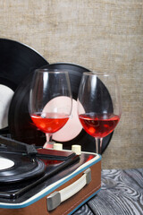 Old turntable. Nearby are two glasses of alcohol. Retro party equipment.