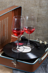 Old turntable. Nearby are two glasses of alcohol. Retro party equipment.