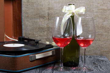 Old turntable. Nearby are two glasses and a bottle of alcohol. Retro party equipment.