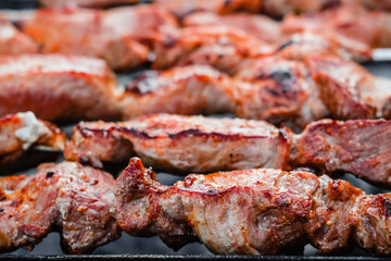 Close up of pieces of pork on skewers fried on the grill.