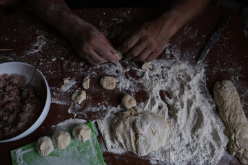 Fototapeta premium Male strong hands sculpt dumplings. A delicious and national dish of Russia. 