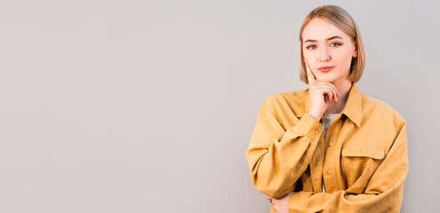 Portrait of a beautiful young woman thinking, isolated on gray background