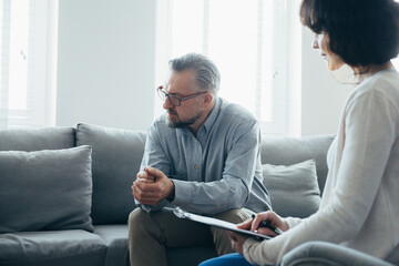 Handsome man sitting on a gray sofa during a meeting with a psychotherapist