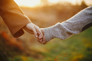 Sensual couple  holding hands in warm sunset light in autumn field, close up. Conceptual image