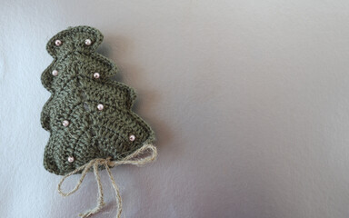 Christmas tree, crocheted, decorated with white beads, on a silver background, space for text, top view