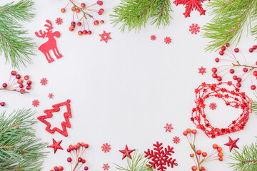 Flat lay frame with red christmas decoration, pine branches on a white background