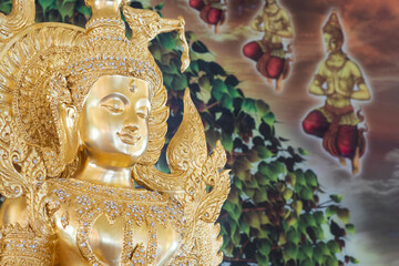 Close up beautiful Thai traditional golden Buddha statue with blurred mural painting on temple wall background
