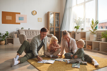 Two parents drawing on the floor together with their two children in the living room