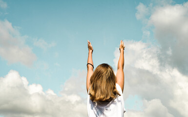 girl against the blue sky, stands with her back to the camera and pulls her hands up. freedom or religion or  financial independence concept © Aleksander Savelev