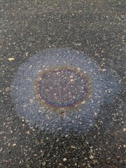 colored stain of engine oil on wet pavement