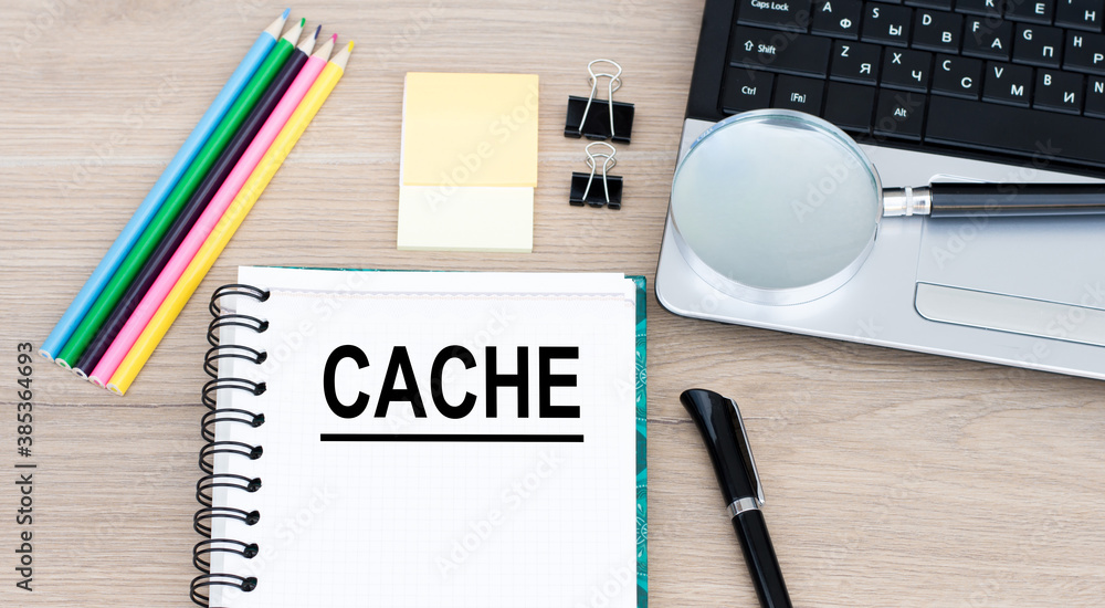 Poster cache on an open notebook that lies on a desk next to a laptop, pen, pencils and a magnifying glass.