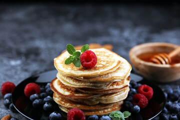 Homemade crepes served with fresh raspberrries and powdered sugar on rustic table.