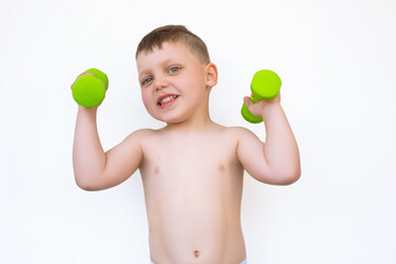 A little boy with green dumbbells smiles on white isolated background