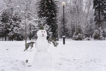 Snowman in the park. Beautiful snowman in front of snow covered trees in winter.