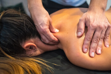 A young woman receiving an upper back massage by a physical therapist. Physio, osteopathy