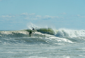 Single surfer rides a wave from Hurricane in Montauk